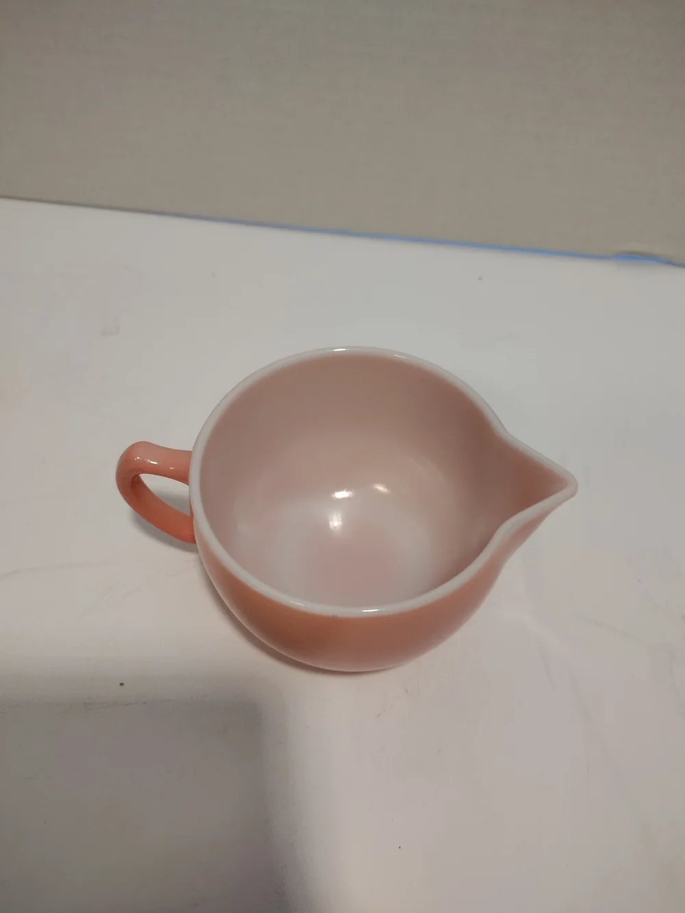 Vintage pink glass creamer by Hazel-Atlas with a C-shaped handle and spout